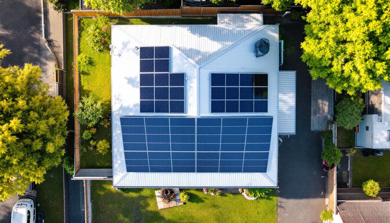 Aerial view of a suburban house with solar panels where a tree casts shade on part of the roof, a key input in any solar calculator NZ estimate